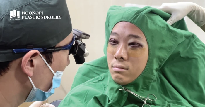 Dr. Nk Park performing a sitting-up symmetry check during ptosis surgery